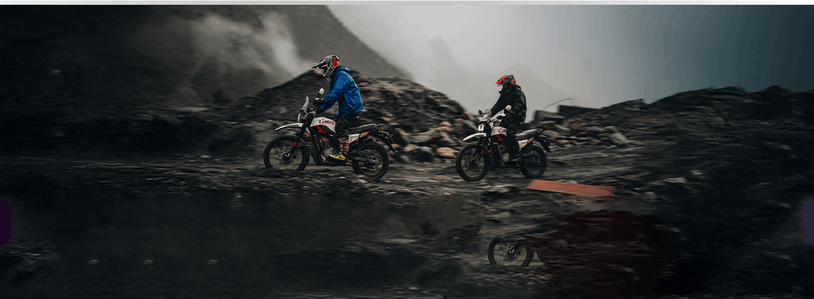 Two riders on Hero Xpulse motorcycles in misty mountains